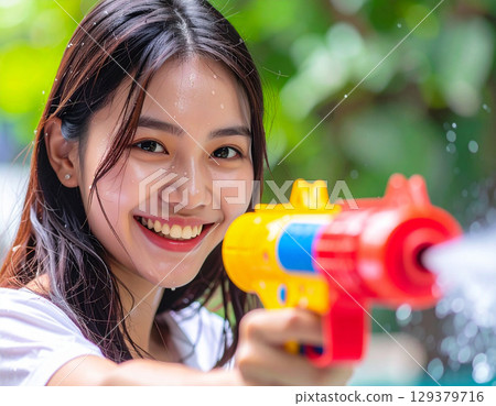 Young woman playing with a water gun Young woman playing with a water gun 129379716