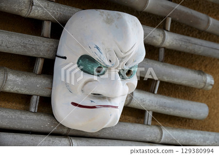 Retro hot spring facility Noh masks displayed on the eaves of an old house 129380994
