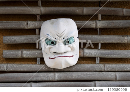 Retro hot spring facility Noh masks displayed on the eaves of an old house 129380996
