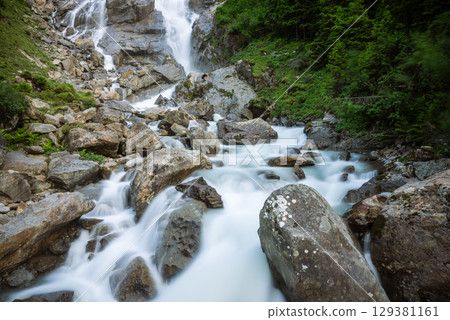 Waterfall flowing through rocky stream in Austrian alpine landscape Waterfall flowing through rocky stream in Austrian alpine landscape 129381161