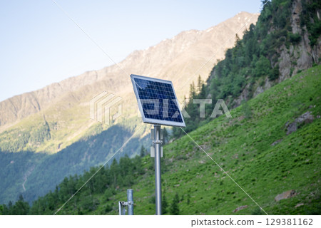 Solar panel in alpine mountain landscape with green hills and blue sky Solar panel in alpine mountain landscape with green hills and blue sky 129381162