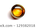 Amber plum wine poured into a clear iridescent glass. A circular composition seen from above. The surface of the drink reflects light. 129382018