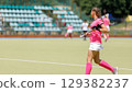 Young athlete plays field hockey in bright pink uniform. Copy space image 129382237