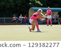 Field hockey player hitting the ball under the bright sun during a game 129382277