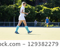 Field hockey player walks on a sunny day during a game at a sports facility 129382279