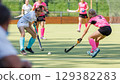 Competitive field hockey match featuring players in action on sunny day 129382283