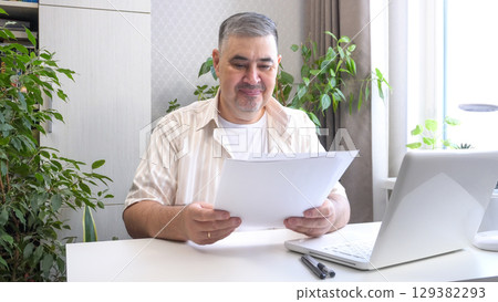 Man Reviewing Work Documents and Smiling Man Reviewing Work Documents and Smiling 129382293