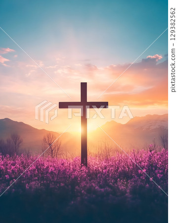 Crucifix silhouette against a vibrant sunset on a mountain backdrop with blooming flowers 129382562