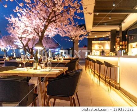 Enjoy a relaxing time at an outdoor bar surrounded by cherry blossoms and illuminated lights. Enjoy a relaxing time at an outdoor bar surrounded by cherry blossoms and illuminated lights. 129383152