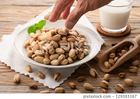 Fragrant pistachios and milk. A natural and stylish food image with a wood grain background and white cloth. 129383167