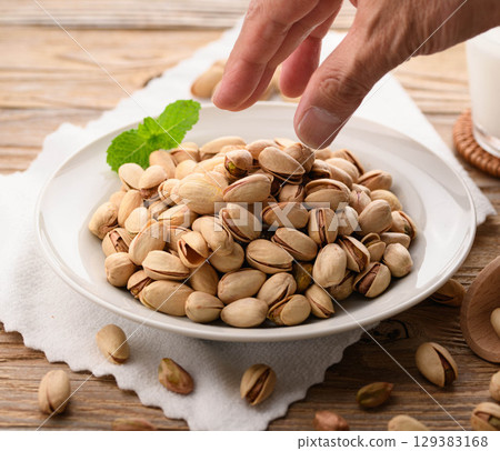 Fragrant pistachios and milk. A natural and stylish food image with a wood grain background and white cloth. 129383168