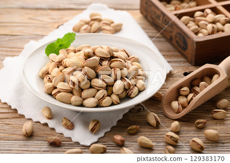 Fragrant pistachios and milk. A natural and stylish food image with a wood grain background and white cloth. Fragrant pistachios and milk. A natural and stylish food image with a wood grain background and white cloth. 129383170