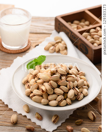 Fragrant pistachios and milk. A natural and stylish food image with a wood grain background and white cloth. 129383173
