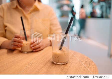 Woman enjoying iced coffee in modern cafe Woman enjoying iced coffee in modern cafe 129383489