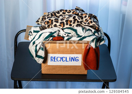 Large box packed with old clothes that are prepared for recycling. Image for Upcycling services. Zero waste concept. Large box packed with old clothes that are prepared for recycling. Image for Upcycling services. Zero waste concept. 129384545