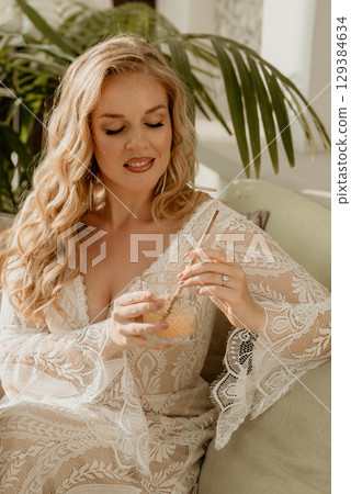Beautiful slim blonde poses in boho wedding dresses and an embroidered corset on a summer terrace Beautiful slim blonde poses in boho wedding dresses and an embroidered corset on a summer terrace 129384634