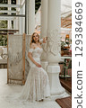 Beautiful slim blonde poses in boho wedding dresses and an embroidered corset on a summer terrace 129384669