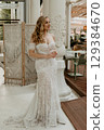 Beautiful slim blonde poses in boho wedding dresses and an embroidered corset on a summer terrace 129384670