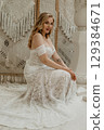 Beautiful slim blonde poses in boho wedding dresses and an embroidered corset on a summer terrace 129384671