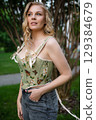 Beautiful slim blonde poses in boho wedding dresses and an embroidered corset on a summer terrace 129384679