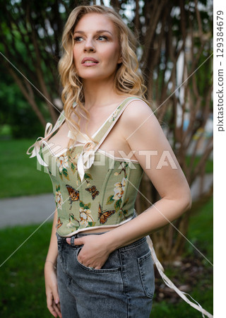 Beautiful slim blonde poses in boho wedding dresses and an embroidered corset on a summer terrace Beautiful slim blonde poses in boho wedding dresses and an embroidered corset on a summer terrace 129384679