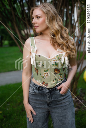 Beautiful slim blonde poses in boho wedding dresses and an embroidered corset on a summer terrace Beautiful slim blonde poses in boho wedding dresses and an embroidered corset on a summer terrace 129384683