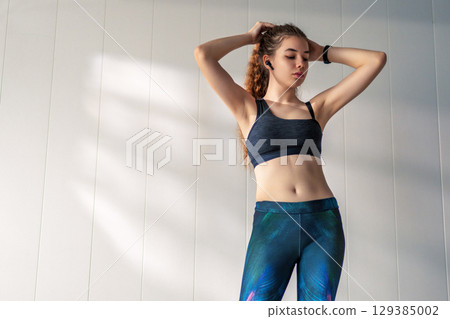 Woman in fashionable sportswear is doing exercise. 129385002