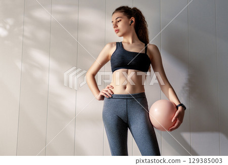 Woman in fashionable sportswear is doing exercise. 129385003