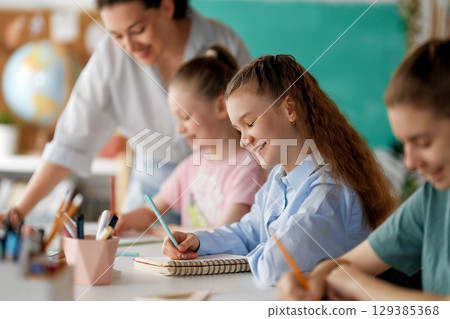 Happy kids and teacher at school Happy kids and teacher at school 129385368
