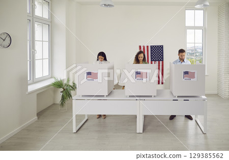 American citizens standing at vote center in voting booth at polling station on election day. 129385562