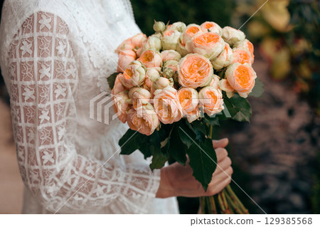 Bouquet in female hands. Bunch of Living Coral roses. Bouquet in female hands. Bunch of Living Coral roses. 129385568