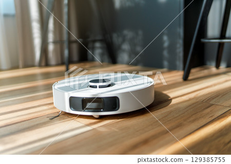 White robotic vacuum cleaner on wooden floor White robotic vacuum cleaner on wooden floor 129385755