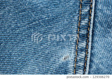 Hole in cotton denim, frayed threads Hole in cotton denim, frayed threads 129386270