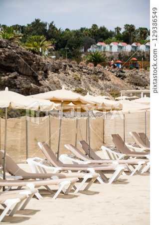 富埃特文圖拉島沿海寬闊的沙灘上擺滿了遮陽傘和沙灘床 富埃特文圖拉島沿海寬闊的沙灘上擺滿了遮陽傘和沙灘床 129386549