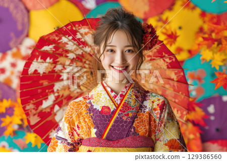A woman wearing a kimono standing in front of an autumn leaf pattern 129386560