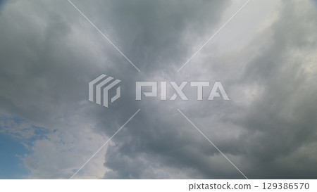 A mesmerizing and dramatic cloudy sky showcasing beautiful shades of gray and blue hues 129386570