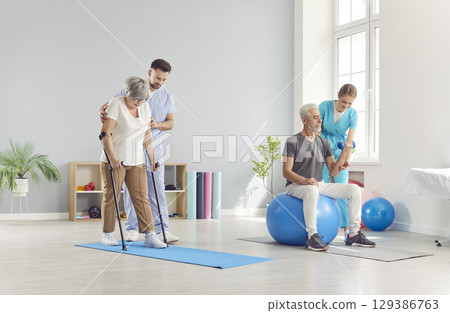 Mature people doing exercises with health care workers in rehabilitation clinic. Mature people doing exercises with health care workers in rehabilitation clinic. 129386763