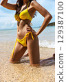 woman in  yellow bikini is posing in the water 129387100