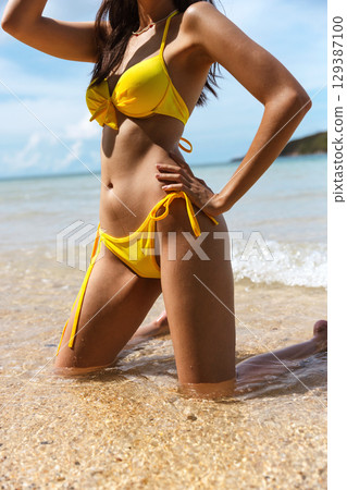 woman in  yellow bikini is posing in the water 129387100