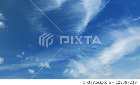 Enjoy the breathtaking view of blue skies with fluffy clouds and contrails across the sky Enjoy the breathtaking view of blue skies with fluffy clouds and contrails across the sky 129387239