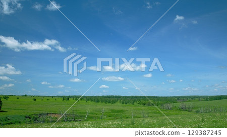A Beautifully Serene and Picturesque Green Landscape Stretching Under a Radiant Bright Blue Sky 129387245