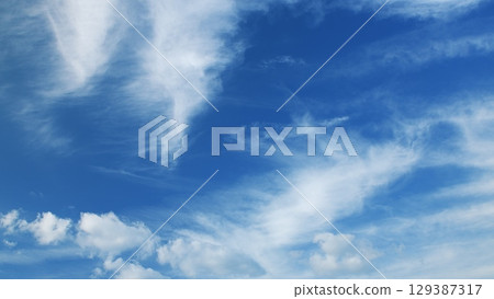 The serene blue sky, adorned with fluffy clouds, creates an inviting and picturesque atmosphere 129387317