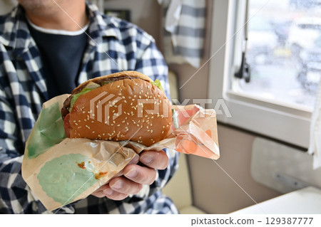 Eating a soul food hamburger (from inside a camper van) Eating a soul food hamburger (from inside a camper van) 129387777