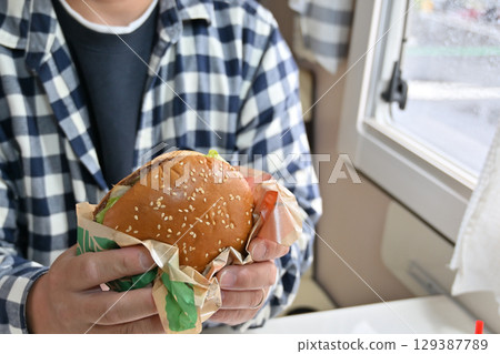 Eating a soul food hamburger (from inside a camper van) 129387789