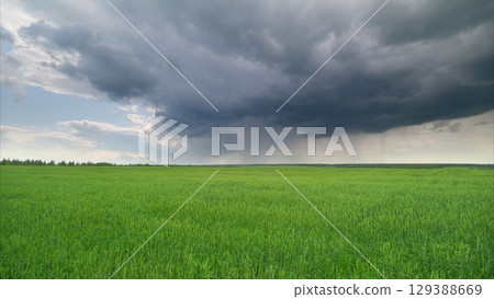 Dramatic and Unpredictable Weather Occurring Above a Lush and Vibrant Green Landscape 129388669