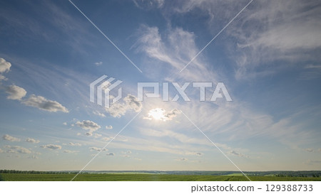 A Beautiful Sunny Sky with Wispy Clouds Gracefully Floating Over Lush Green Fields A Beautiful Sunny Sky with Wispy Clouds Gracefully Floating Over Lush Green Fields 129388733