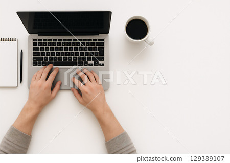 辦公桌場景：一個人在用筆記型電腦工作，喝著咖啡 129389107