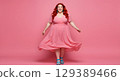 happy smiling woman in dress posing on pink background 129389466