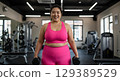 smiling fit brunette posing at gym 129389529