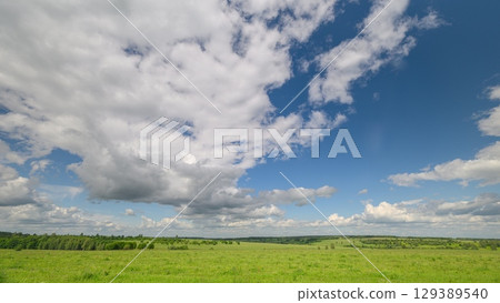 An Expansive Green Landscape Featuring Dynamic Clouds in the Bright Blue Sky Above 129389540